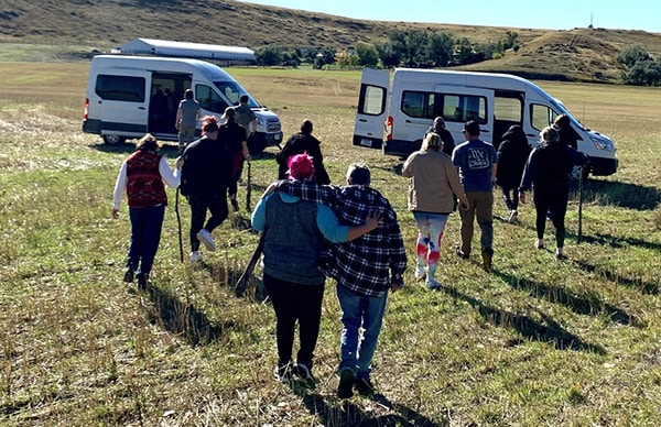building-community A group of people walking through a field towards some vehicles