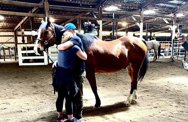 family-focused-2 Two people hugging, standing next to a horse